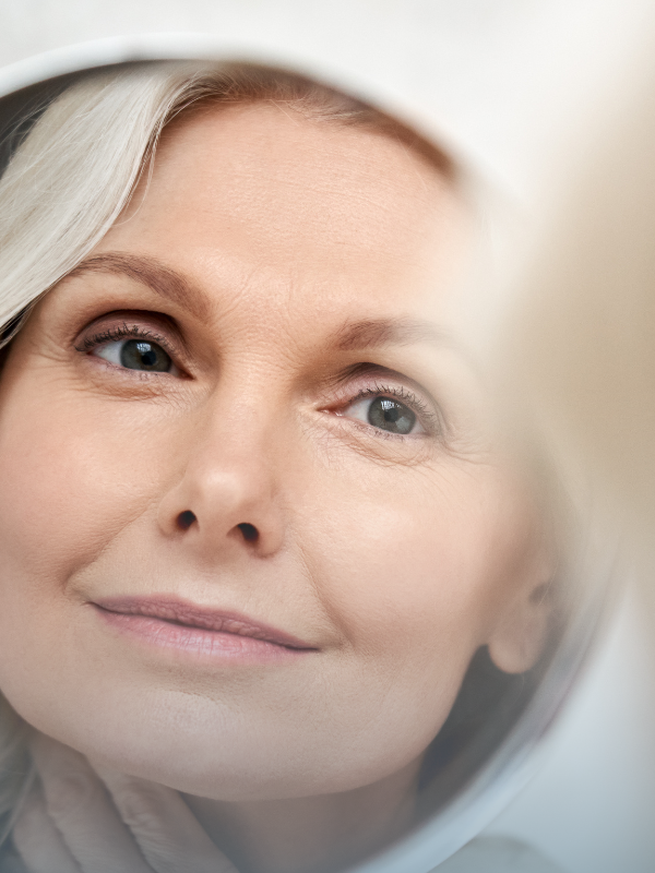 Older woman with smooth skin looking in mirror